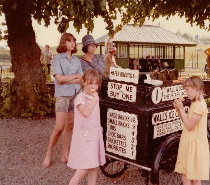  Tamzin in pink and and Perry in yellow eating ice creams whilst appearing as film extras in 'Swallows & Amazons'. Kit Seymour and Jane Grendon stand behind them.