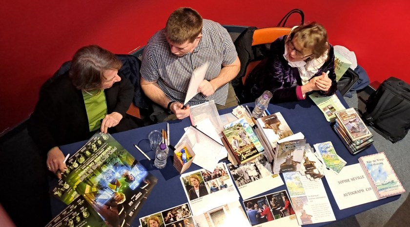 Sue Anstruther and Sophie Neville signing books with the help of Alex Moore